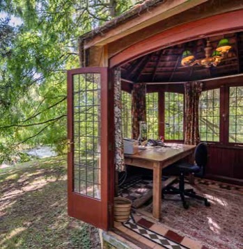 Inside the summer house: a desk, a patterned tiled floor and leaded windows all round.