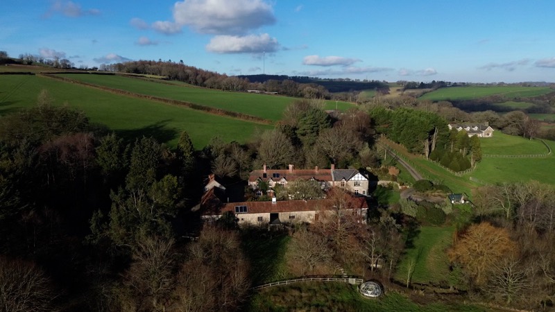 Aerial view showing the house and the neighbouring wing among trees on a clear winter day.
