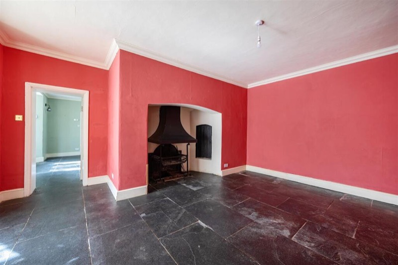 The dining room with red walls and a wide inglenook with an iron hood.