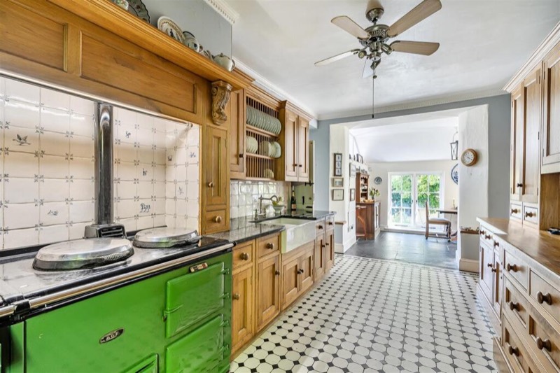 The kitchen with a green Aga in a tiled recess and oak cupboards.