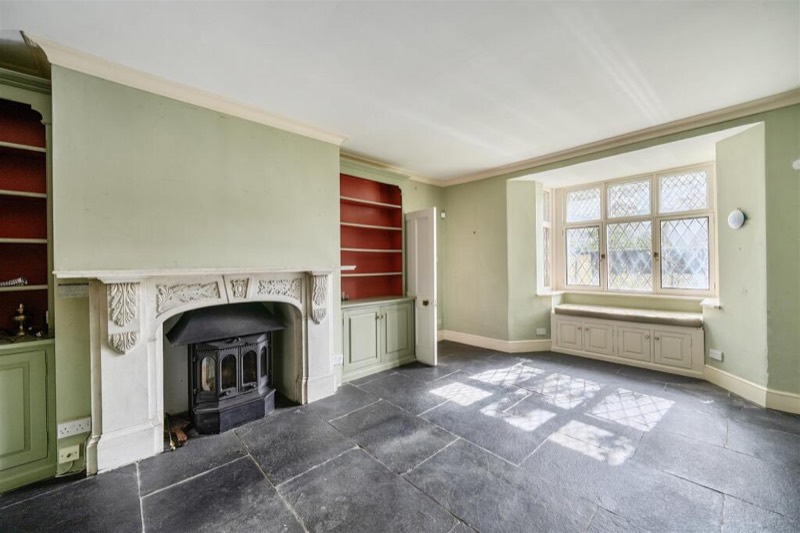 A green-painted room with a marble chimneypiece, fitted shelving and a window seat.